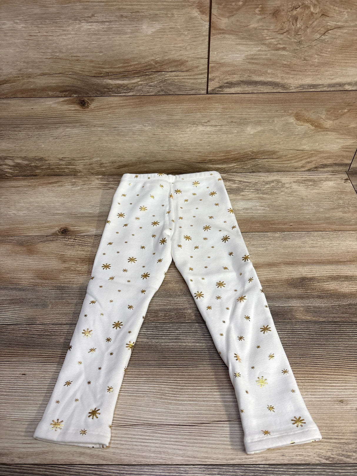 White baby leggings with gold star pattern on wood floor