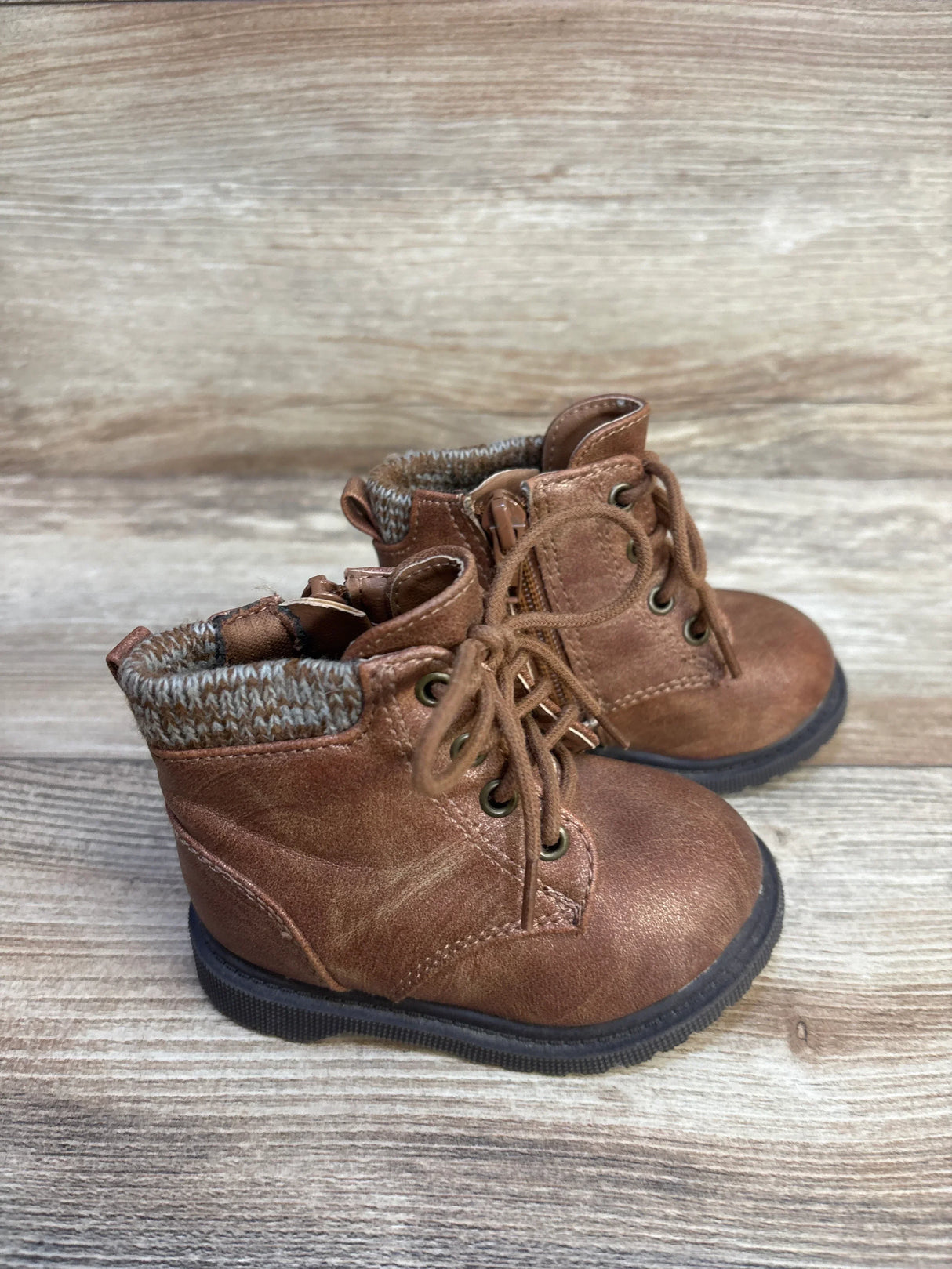 Brown toddler lace-up boots with knit ankle cuffs on a wooden background
