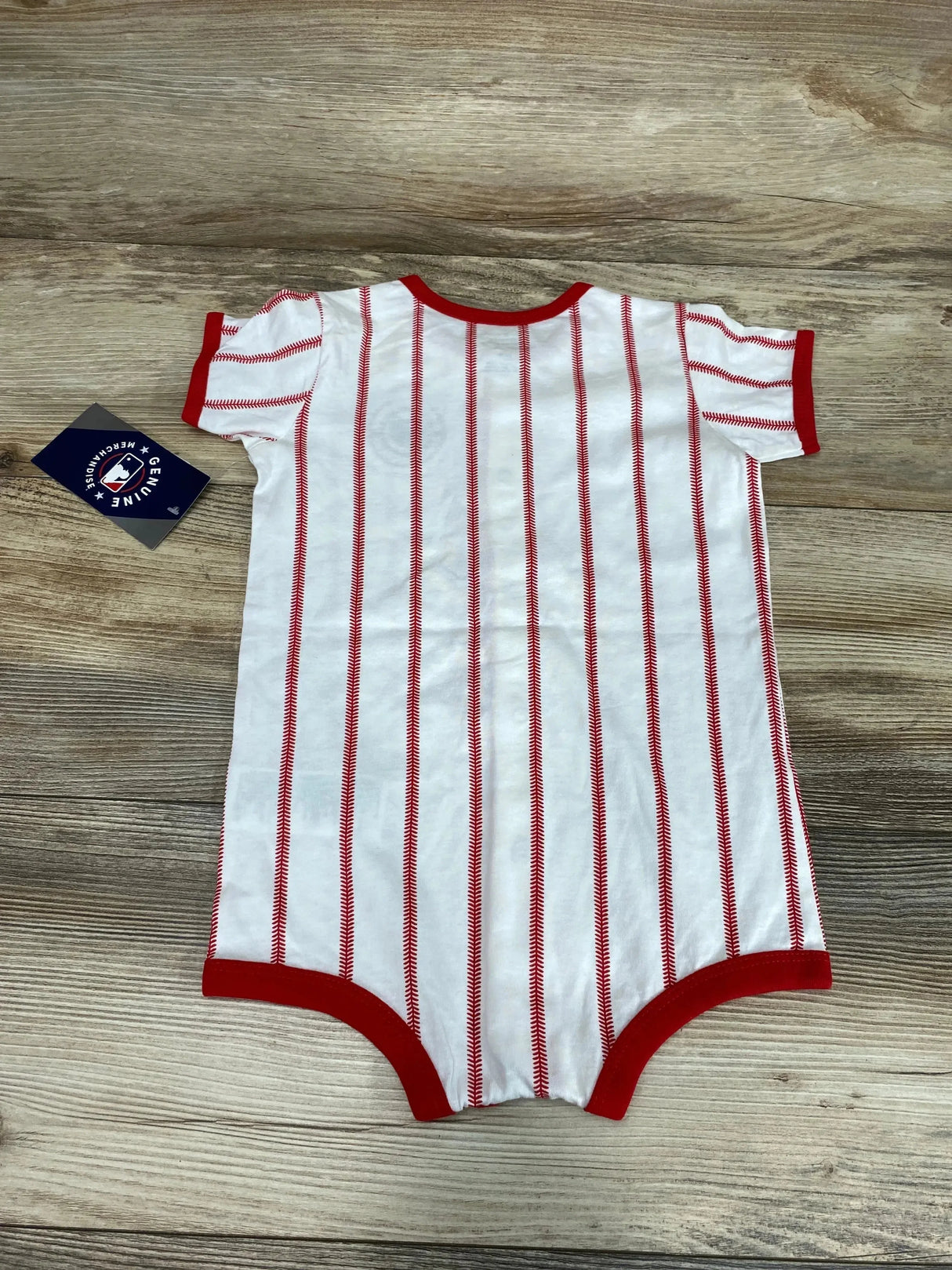 Top-down view of white baby creeper with red baseball-stitch vertical stripes and red trim on wooden background