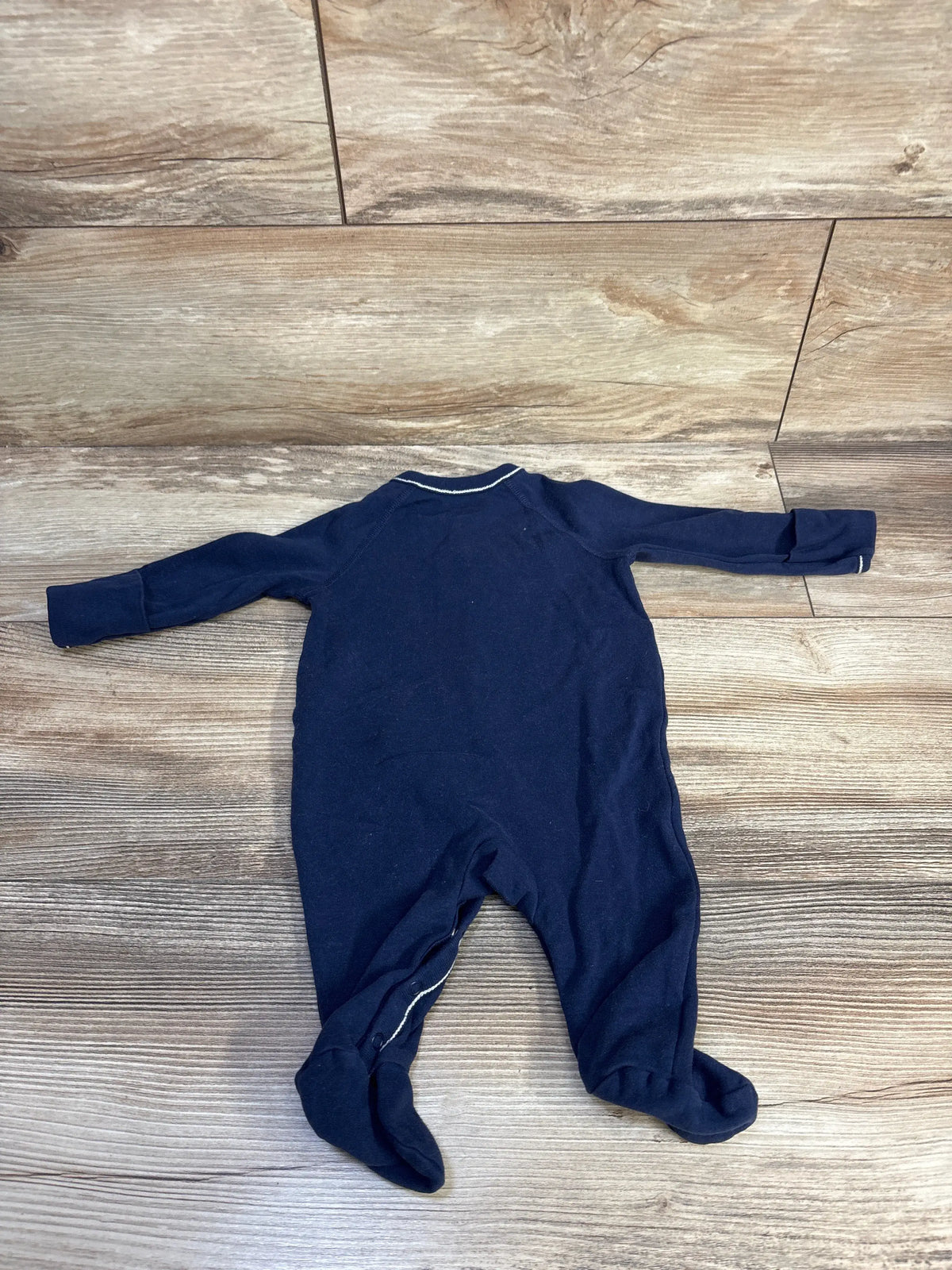 Back view of Ralph Lauren navy cotton jersey footed coverall, size 3 months, with long sleeves on wood-look flooring