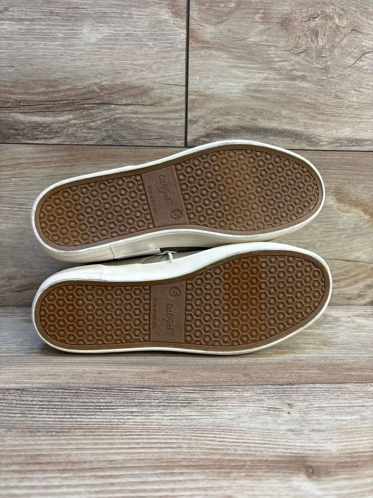 Bottom view of Cat & Jack Jakob kids’ grey boots size 5Y showing brown hex-pattern rubber soles with light wear on wood floor