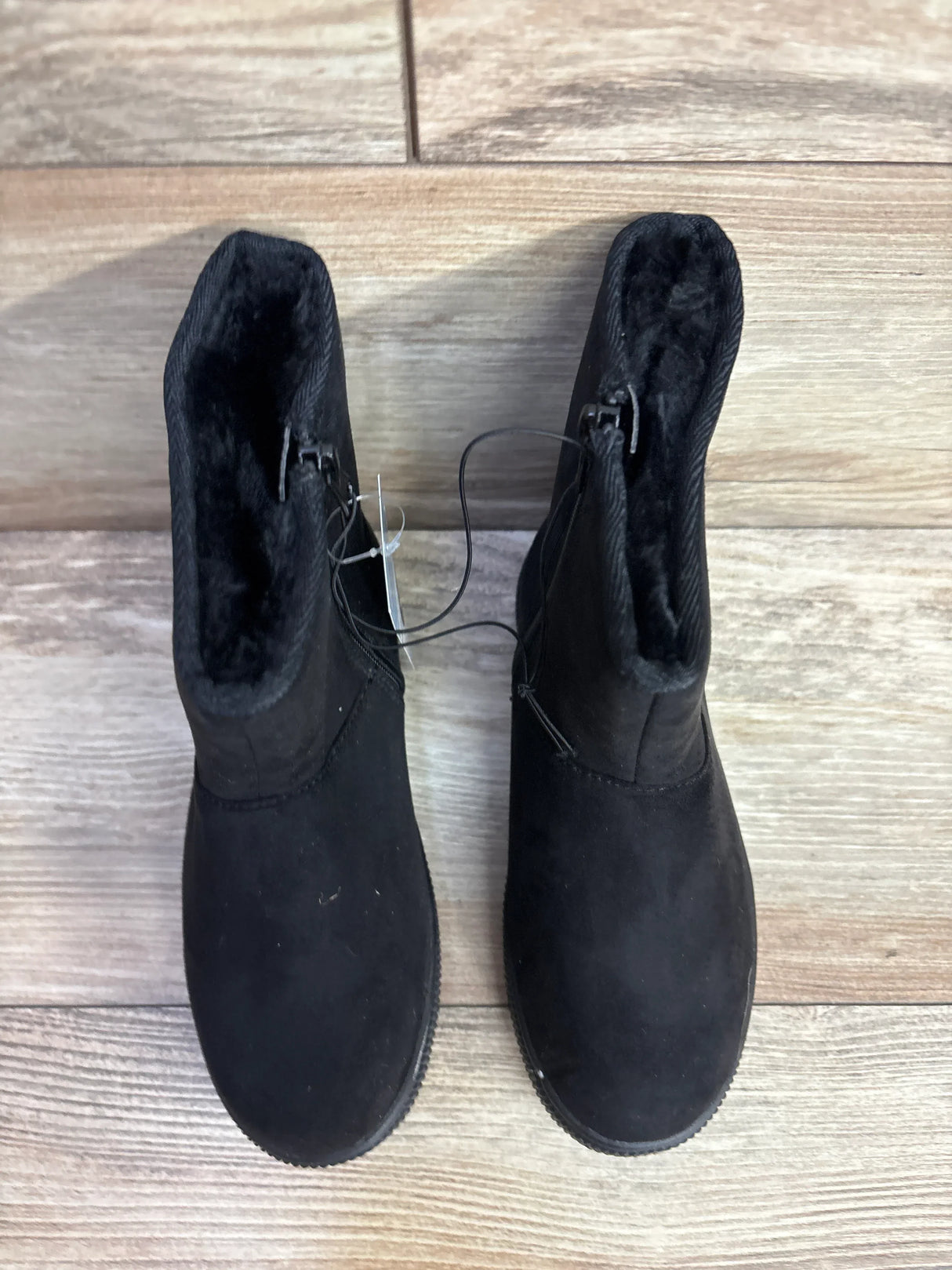 Pair of black suede kids boots with black fur lining on wood floor