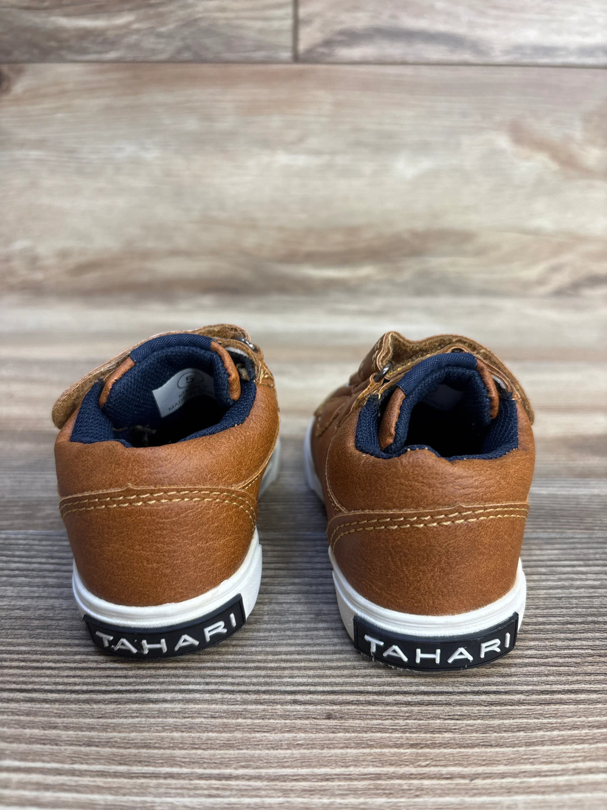 Tan Tahari toddler shoes with navy lining and white soles, size 5, on wood floor