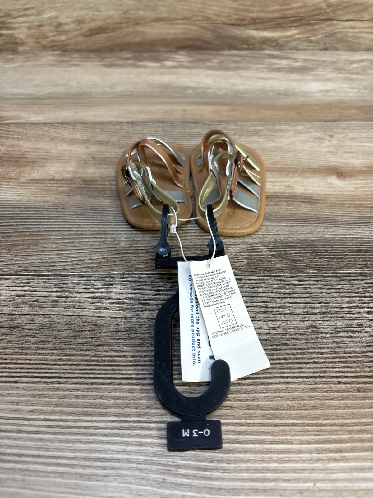 Infant sandals 0-3 months with metallic straps on wood background, resale baby shoes