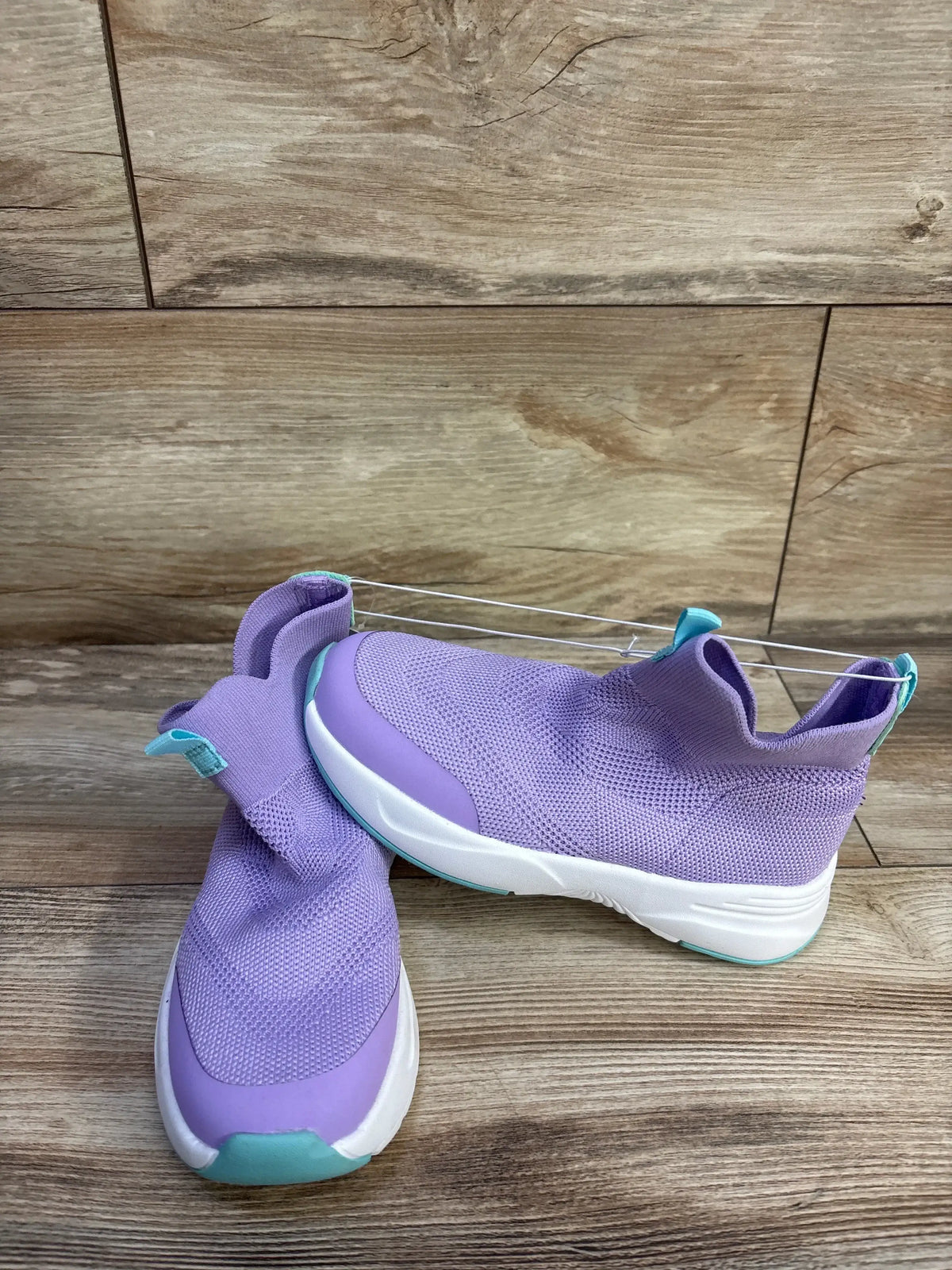 Front and side view of Cat and Jack Ari toddler purple sneakers with knit upper, white sole and mint accents on wood background