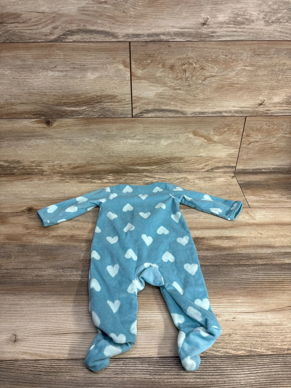 Blue footed baby sleeper with white heart pattern on wooden background