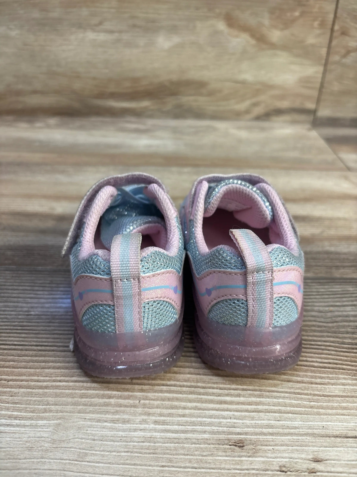 Rear view of pink Skywheel light-up sneakers showcasing mesh panels and translucent soles on a wood floor
