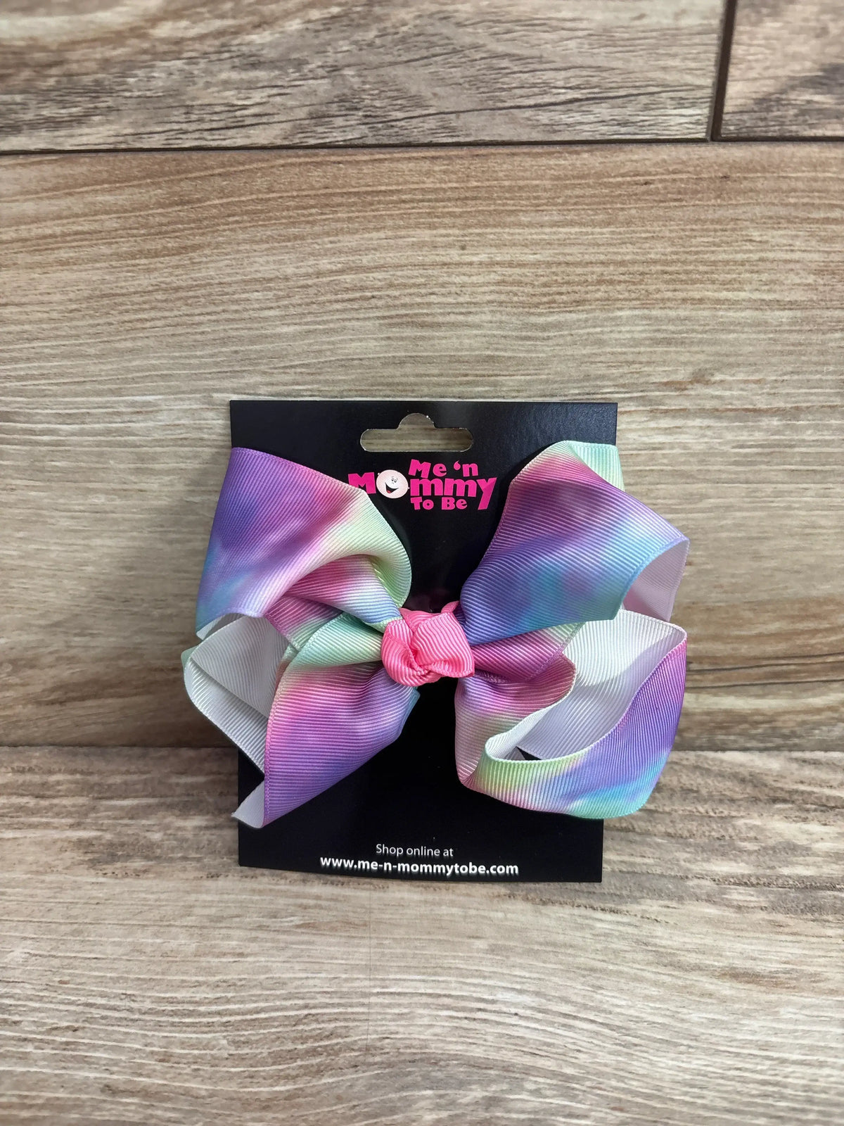 Front view of NEW Large Hair Bow showcasing oversized pastel rainbow loops on a black display card over a wood plank floor