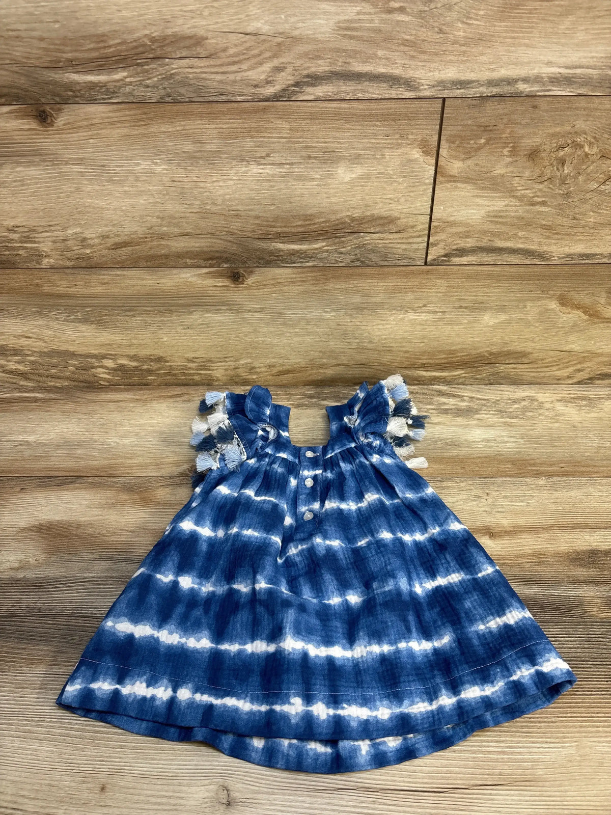 Blue and white tie-dye toddler dress with ruffle sleeves on wooden background