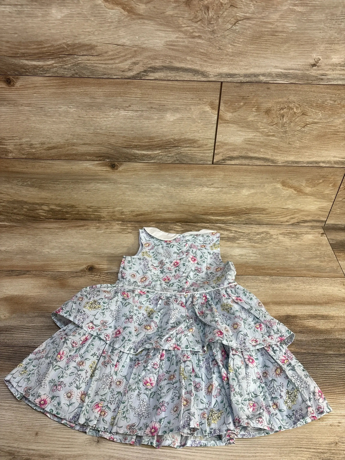 Flat-lay of Girls Janie & Jack light blue floral dress, size 2T, with white collar and tiered ruffle skirt on wood floor