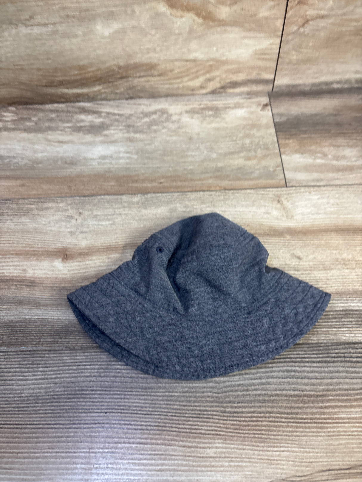 Flat-lay of Old Navy baby swim bucket hat size 0-6M showing blue heather fabric, stitched brim and side eyelets on wood floor
