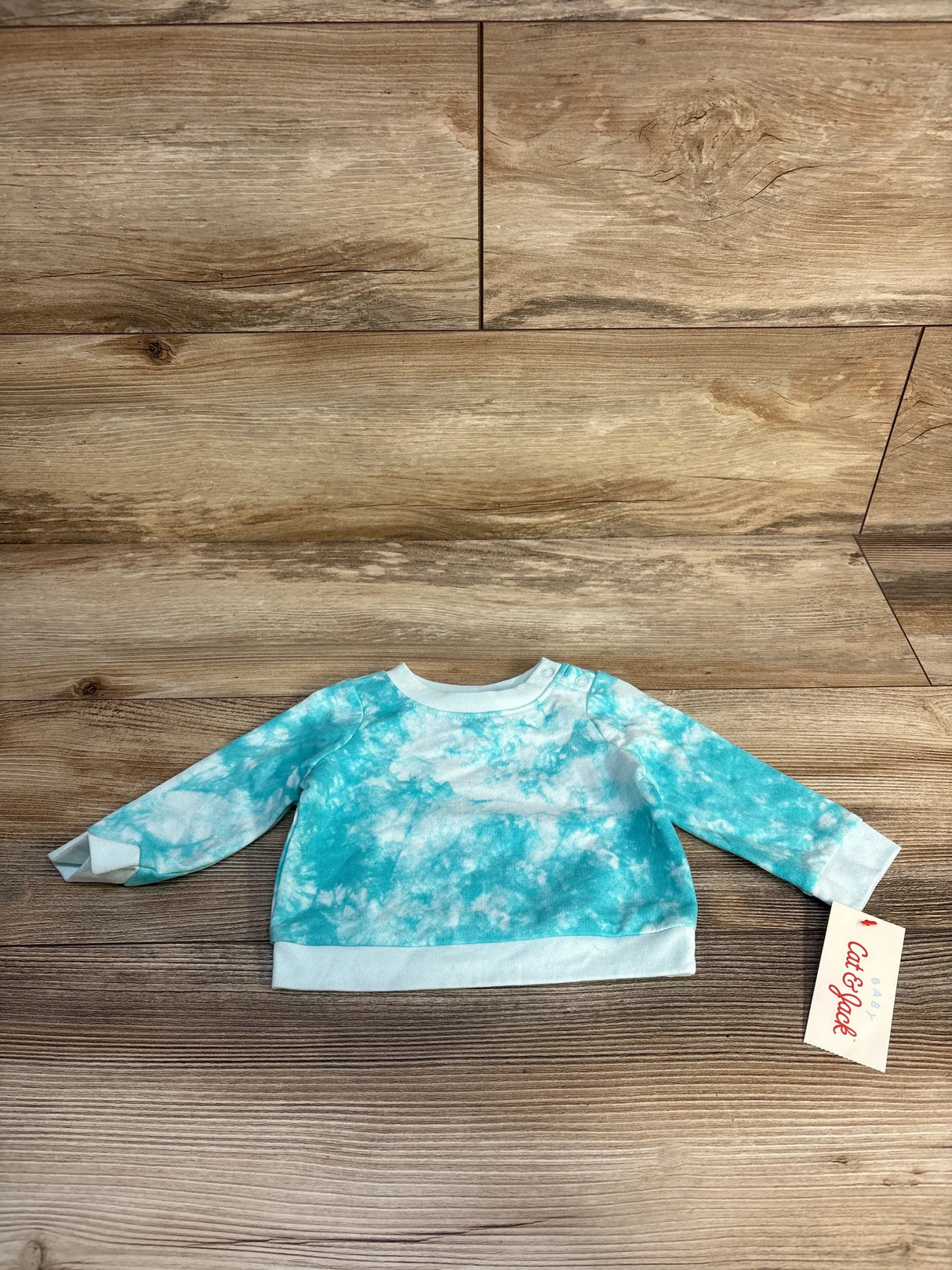 Blue and white tie-dye long sleeve baby sweatshirt on wooden background with tag