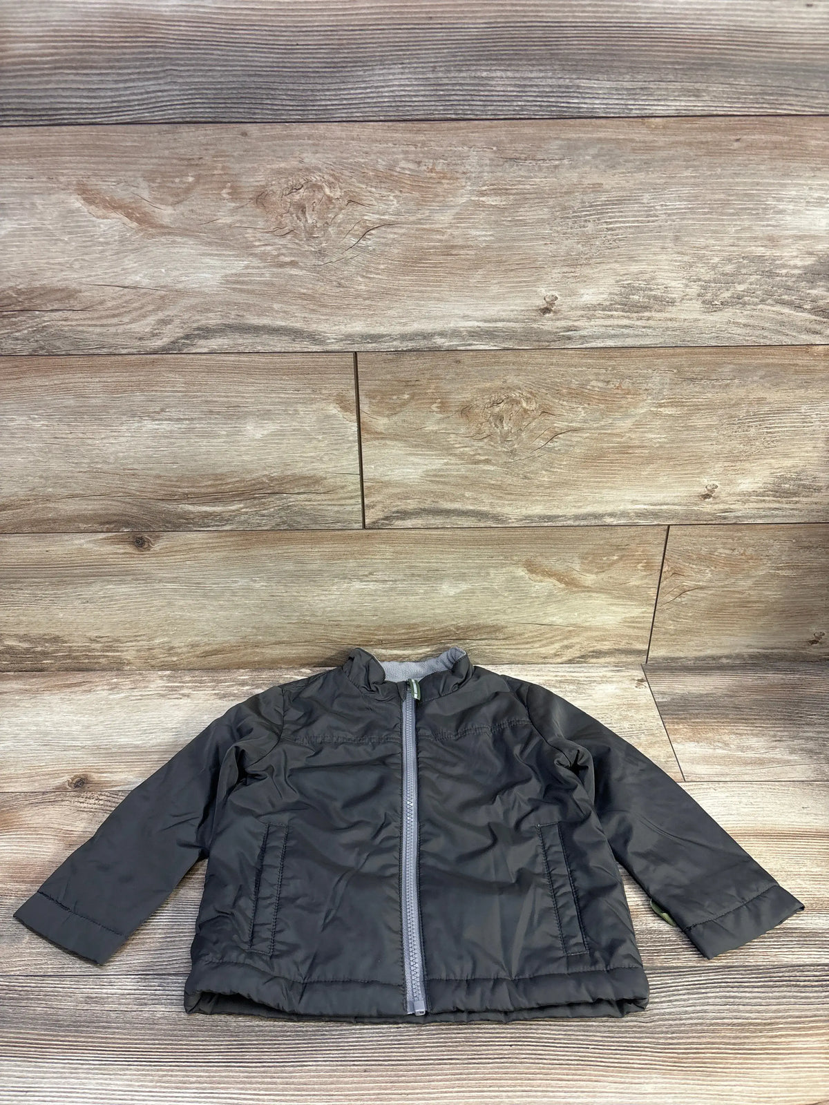 Front view of Cat & Jack toddler green lined windbreaker jacket with zipper and side pockets on wood background