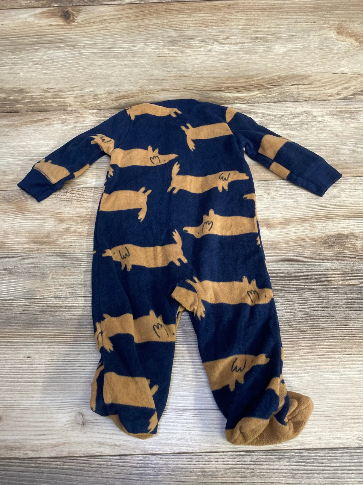 Flat-lay of navy Carter's dog-print blanket sleeper (size 6M) showing footed legs and all-over tan dog pattern on a wood floor