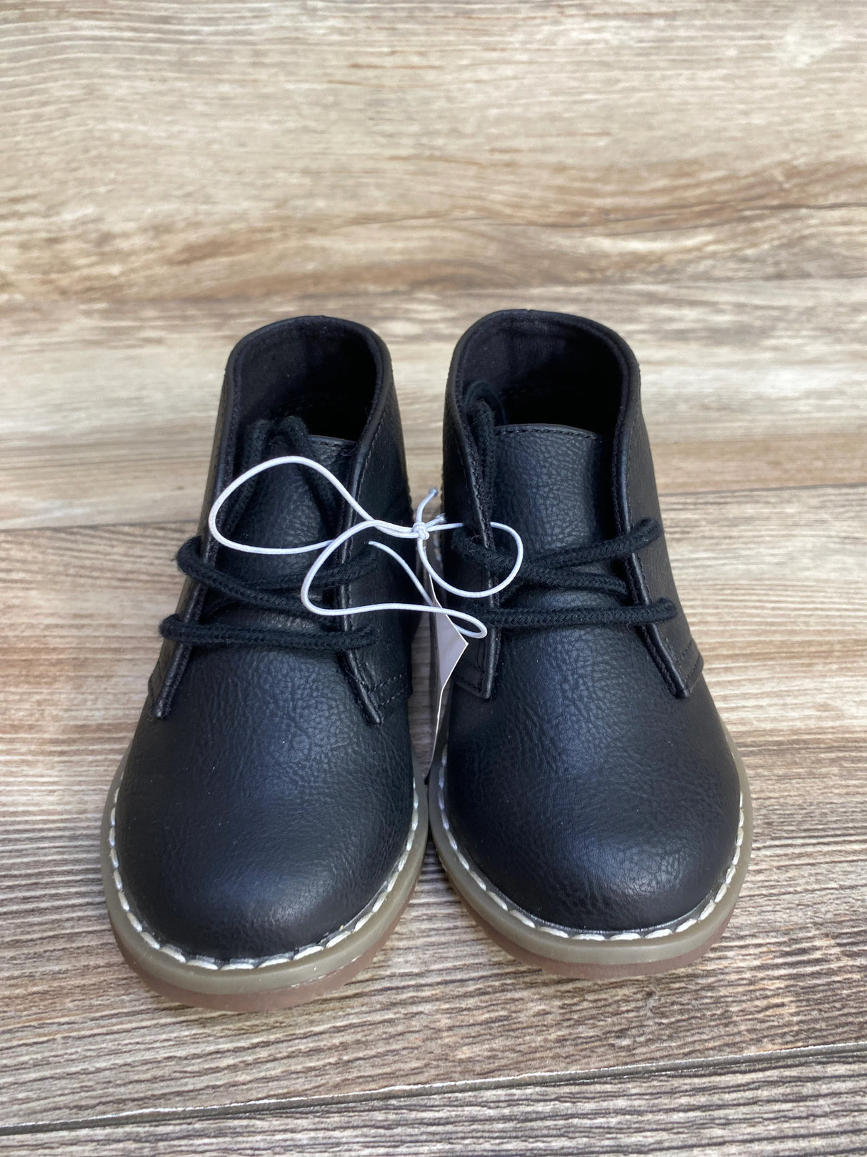 Black leather toddler boots with black laces on wooden floor