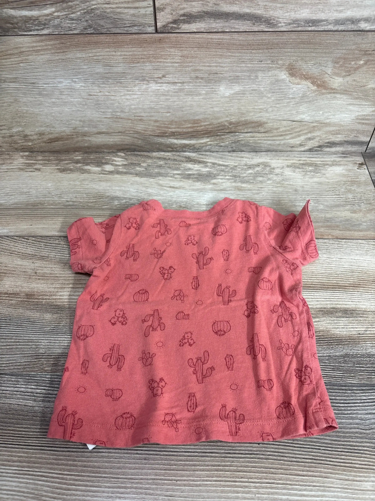 Front view of red Baby Gap cactus print pocket shirt with short sleeves and chest pocket on wood-grain background