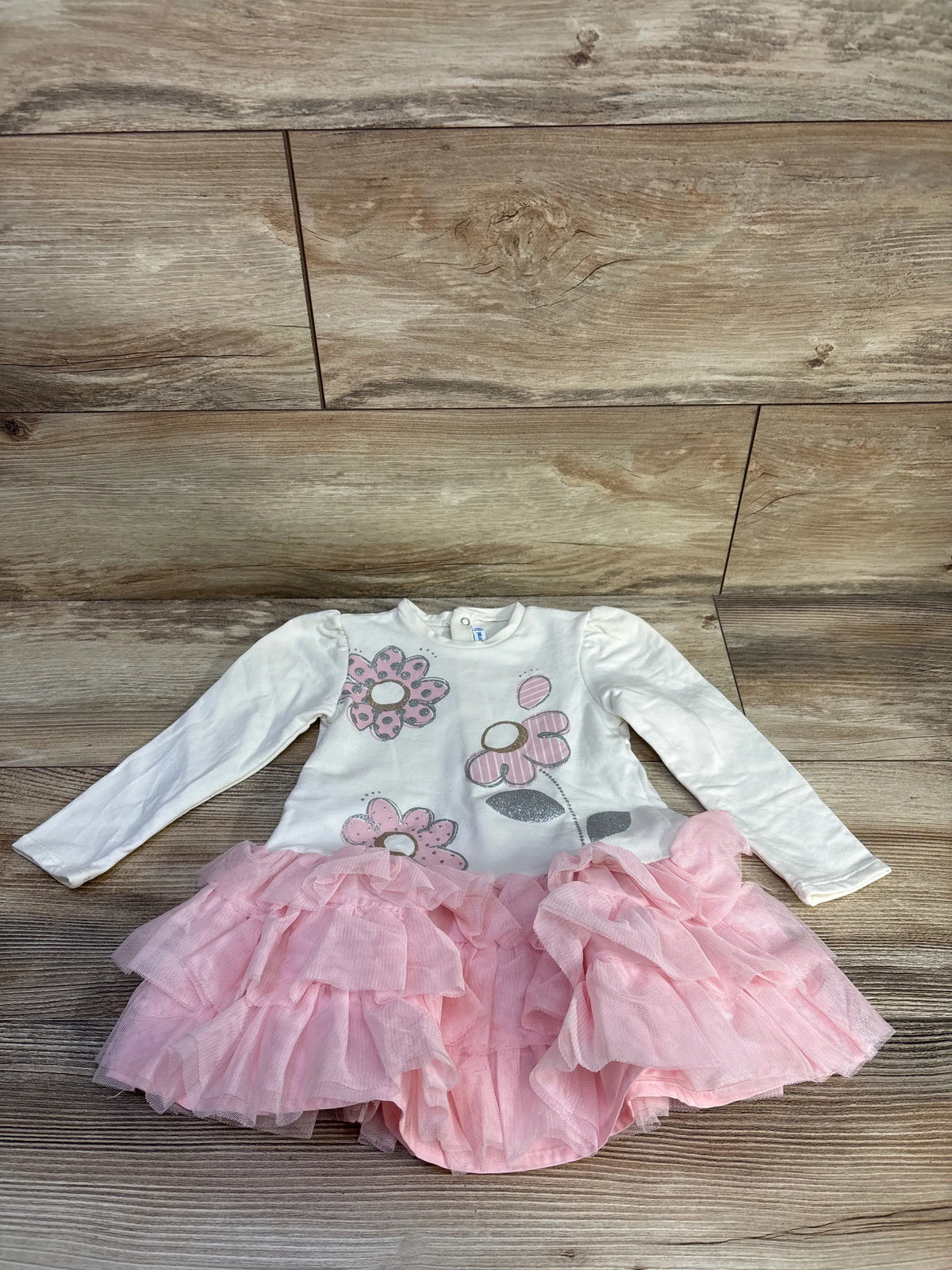 Front view of Mayoral long sleeve pink tulle dress showcasing a floral-print ivory bodice and layered pink tulle skirt on a wood floor
