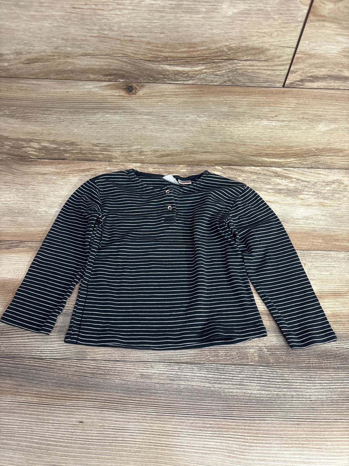 black and white striped long sleeve toddler shirt with buttons on wooden floor