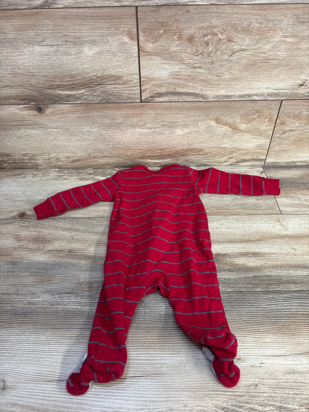 Front view of Just One You striped red sleeper showcasing long sleeves and footed legs on a wood-look floor