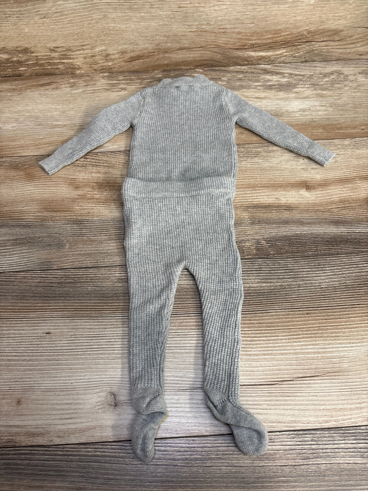 Flat lay of NooVel grey ribbed thermal shirt and footed pants 2-piece set 3M showcasing ribbed knit on wood background