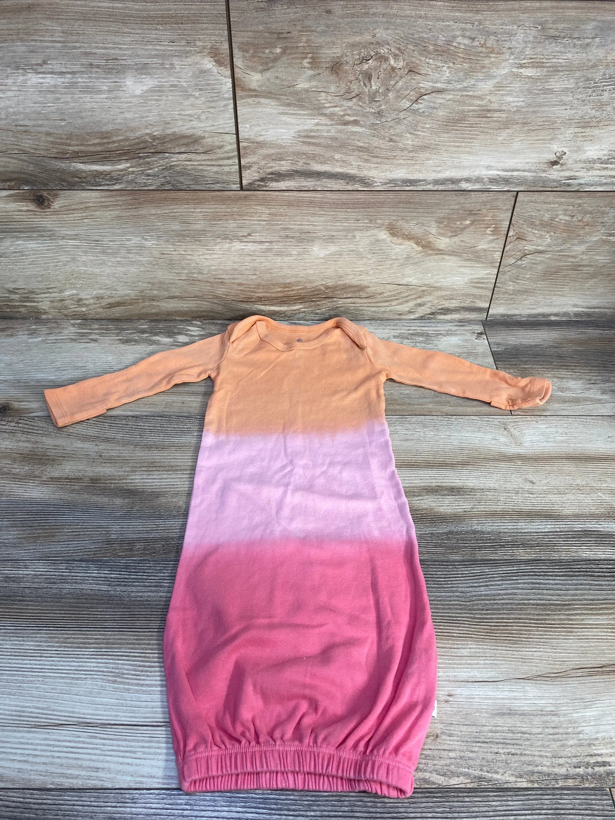 Front view of Honest Baby organic cotton sleep gown showing long sleeves and ombre orange, lavender, and pink coloring on wood-look flooring