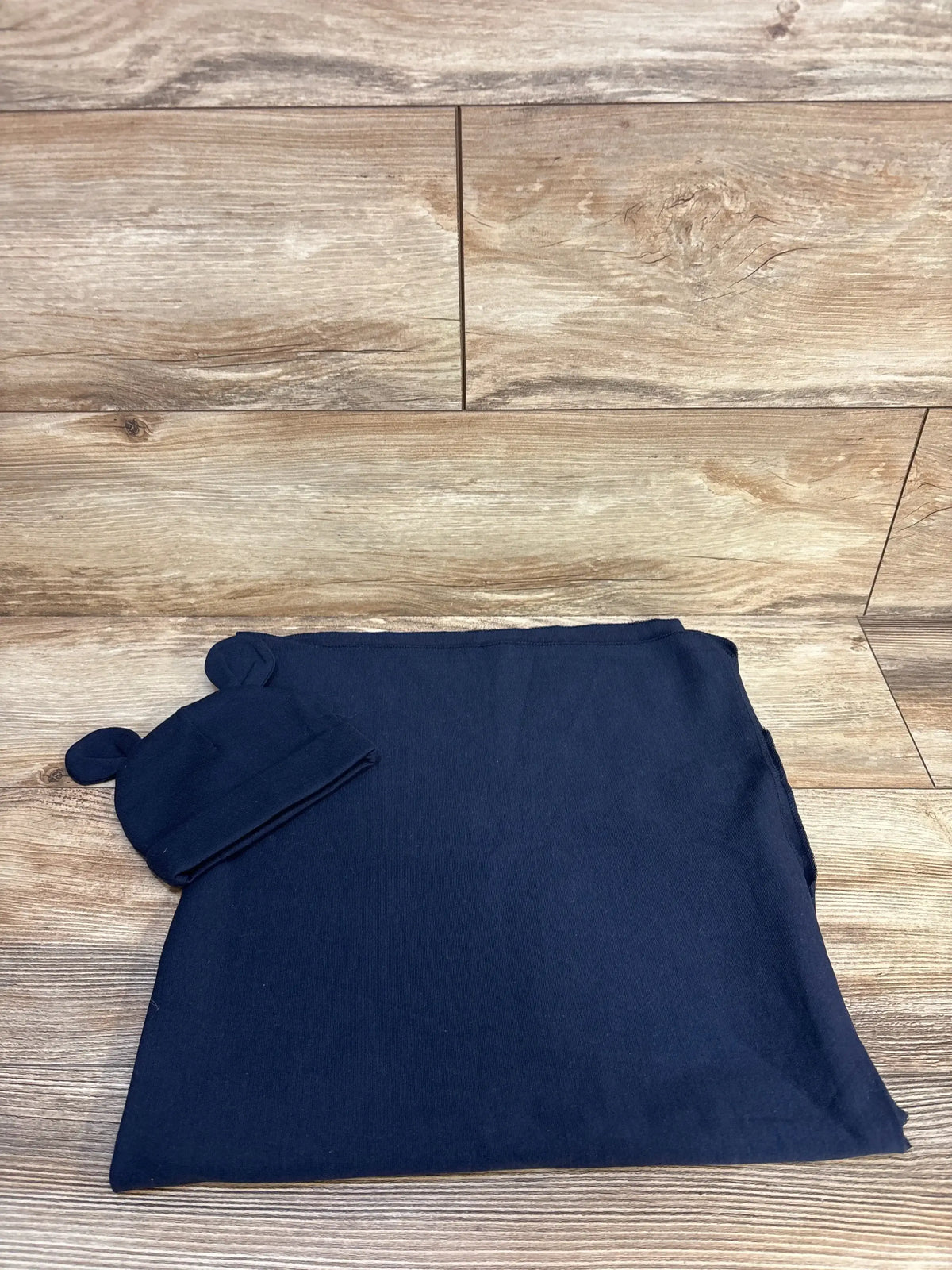 Navy blue baby blanket and beanie hat with bear ears on wood background