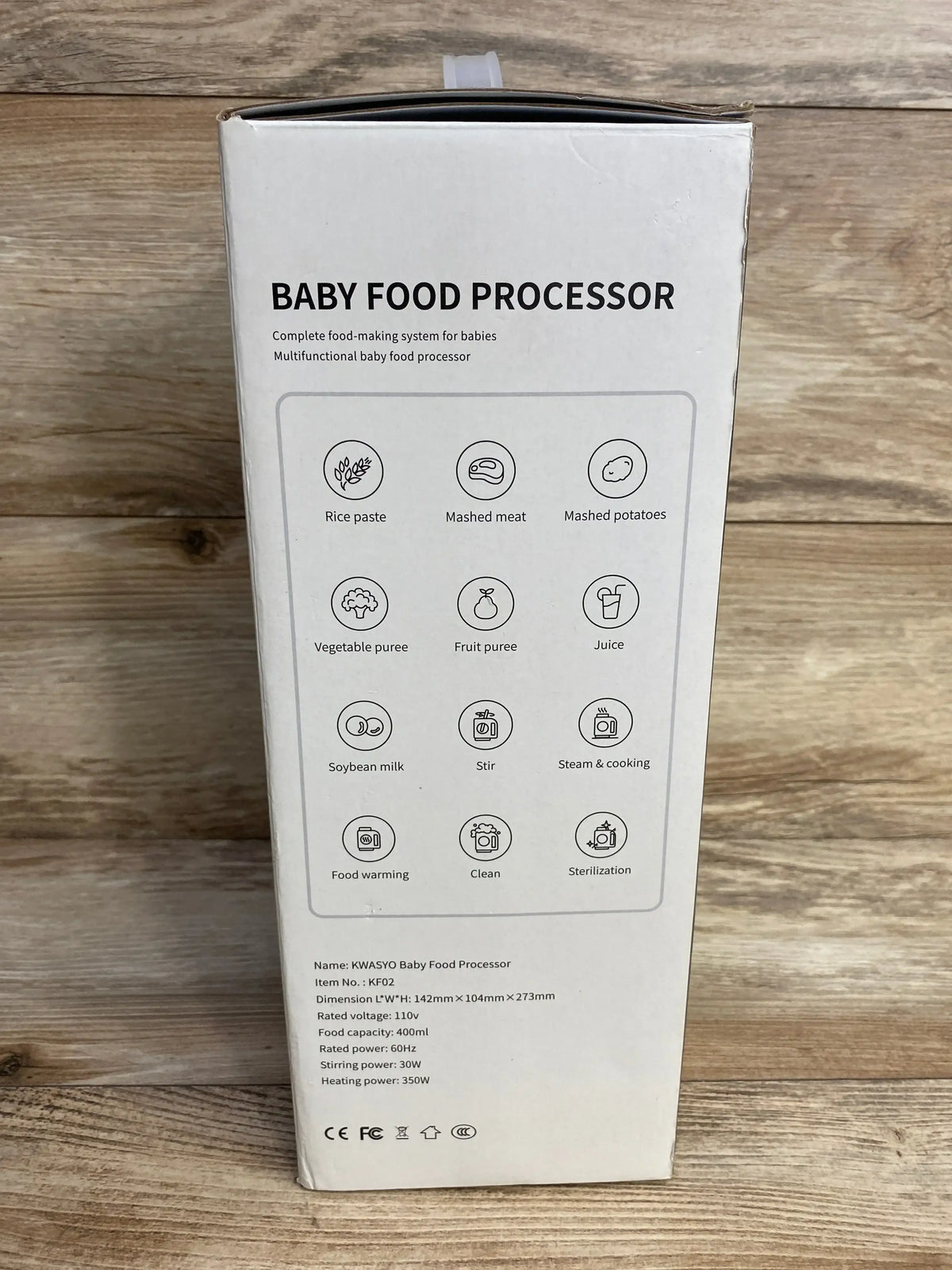 Front of KWASYO baby food processor box showing headline BABY FOOD PROCESSOR and function icons on a wooden background