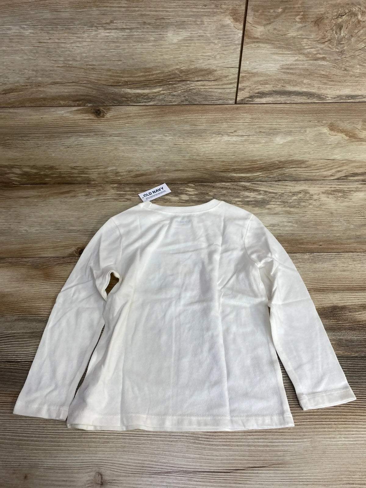 Back view of white Old Navy ballerina shirt in size 4T showing long sleeves and plain back on a wooden background