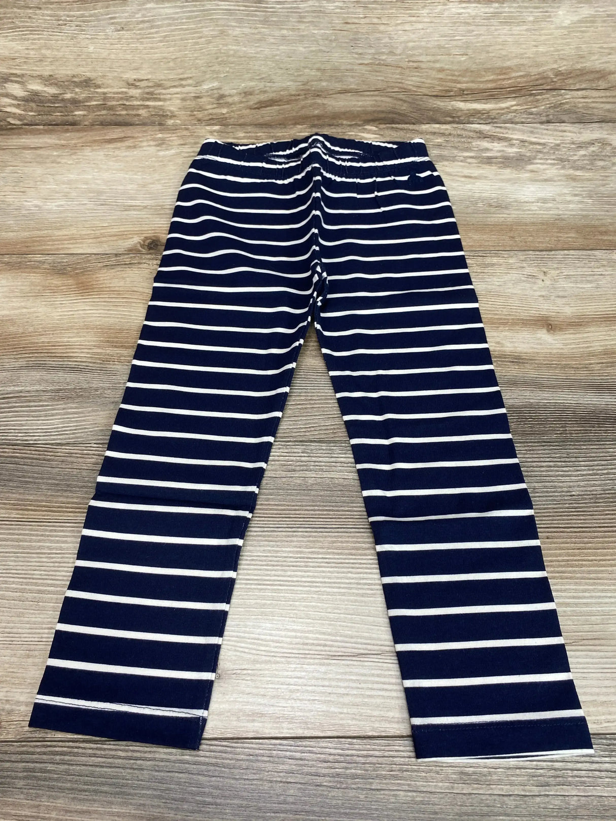 Flat lay of Baby Gap navy and white striped leggings with elastic waistband on wood floor, size 3T