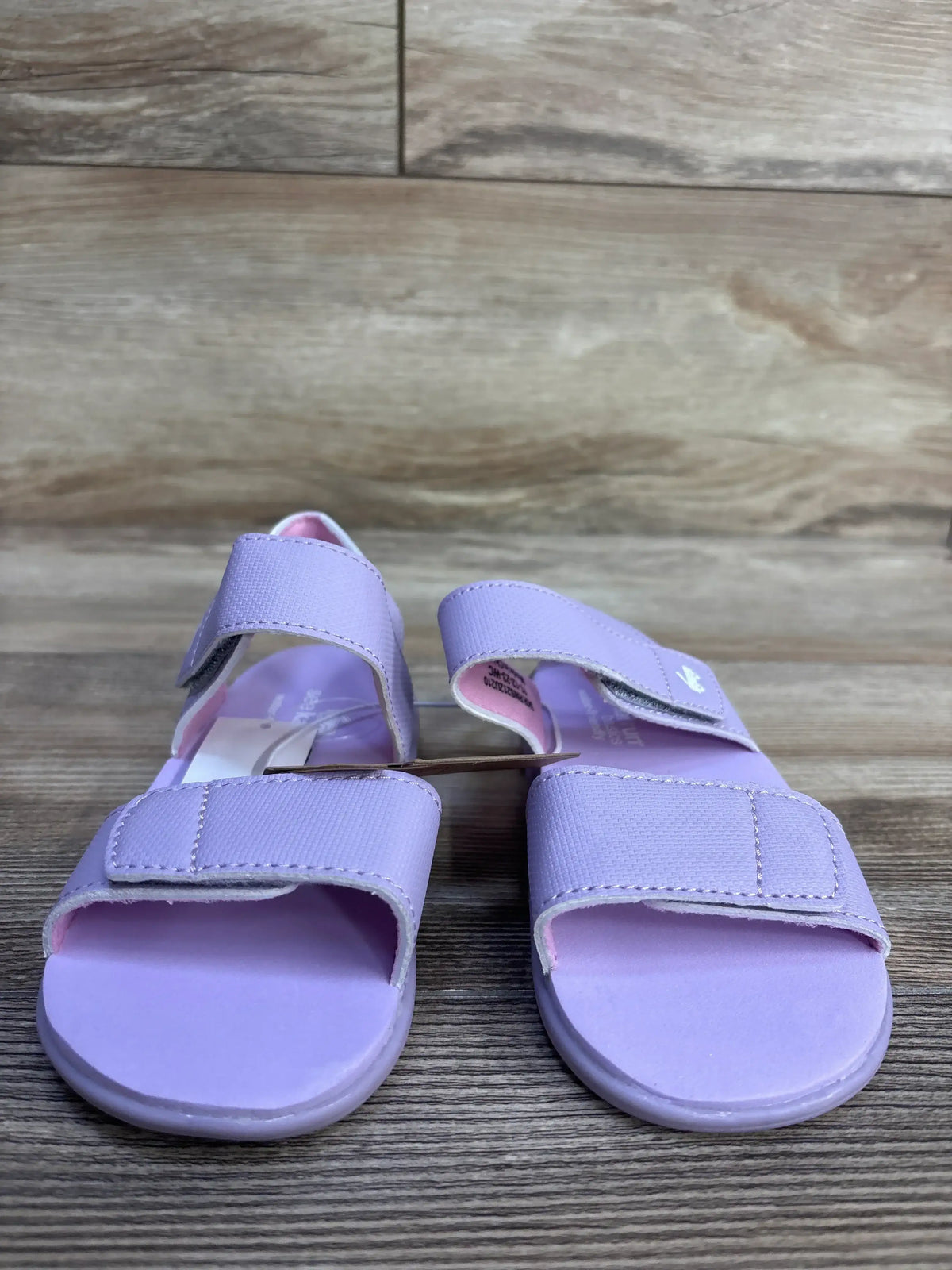 Front view of lavender See Kai Run Jaylen toddler sandals showcasing two adjustable Velcro straps and open toe with wood plank background