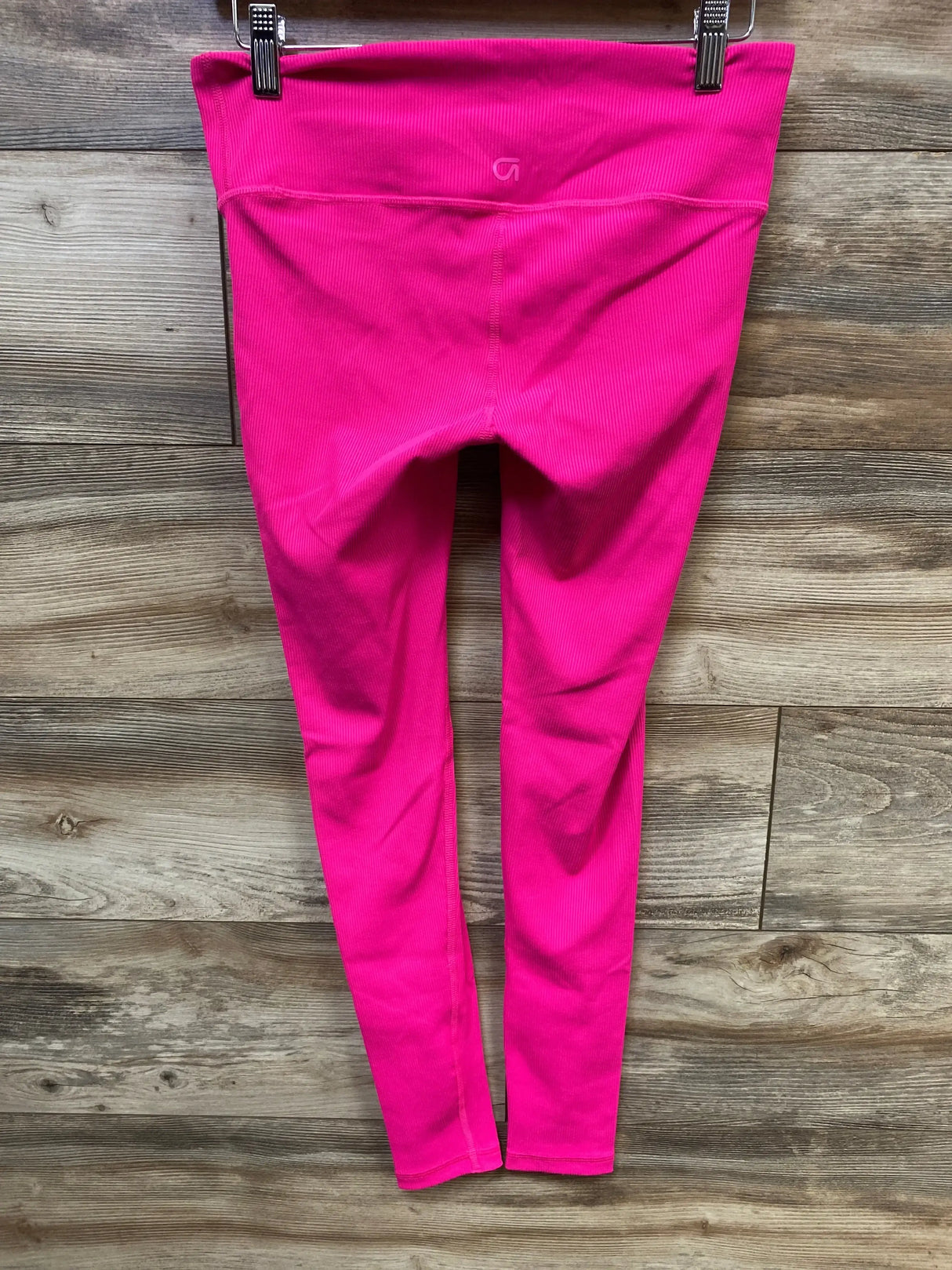 Front view of pink GapFit maternity leggings with under-belly ribbed waistband and blackout fabric, size XS, hanging on wooden plank background