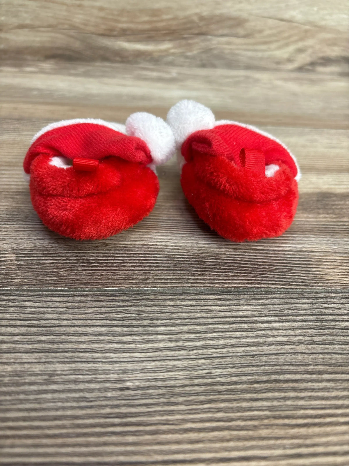 Red and white baby booties with fluffy pom-poms, perfect for newborns and infants.