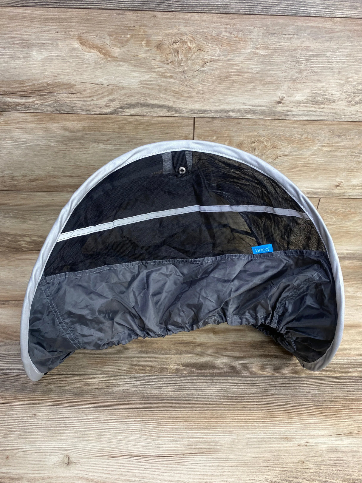 Brica stroller sunshade canopy with mesh panel on wood floor, baby gear accessory