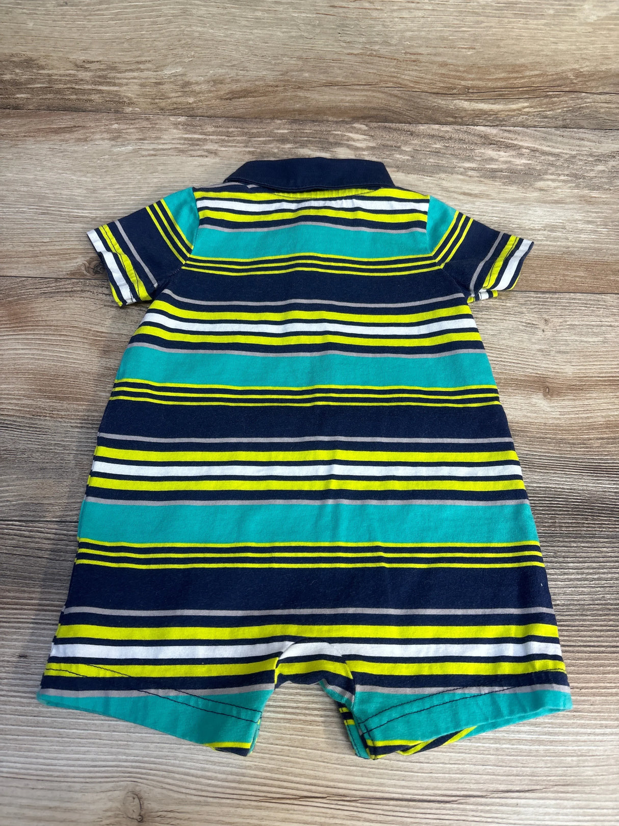 Striped short sleeve baby romper with navy, teal, yellow, and white pattern on wood background