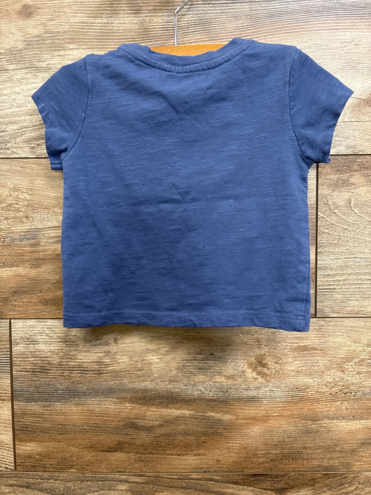 Back view of Roxy floral toddler shirt showcasing short sleeves and crew neckline with slub knit texture on wooden background