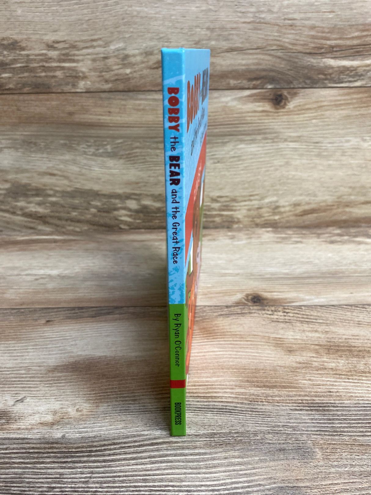 Spine of children's book titled Bobby the Bear and the Great Race by Ryan O'Connor on wood surface