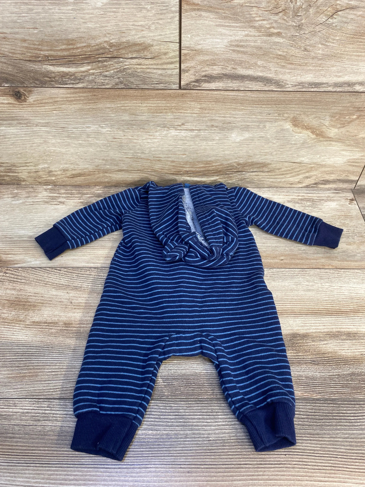 Navy blue and white striped baby romper with zipper, long sleeves, on wood background