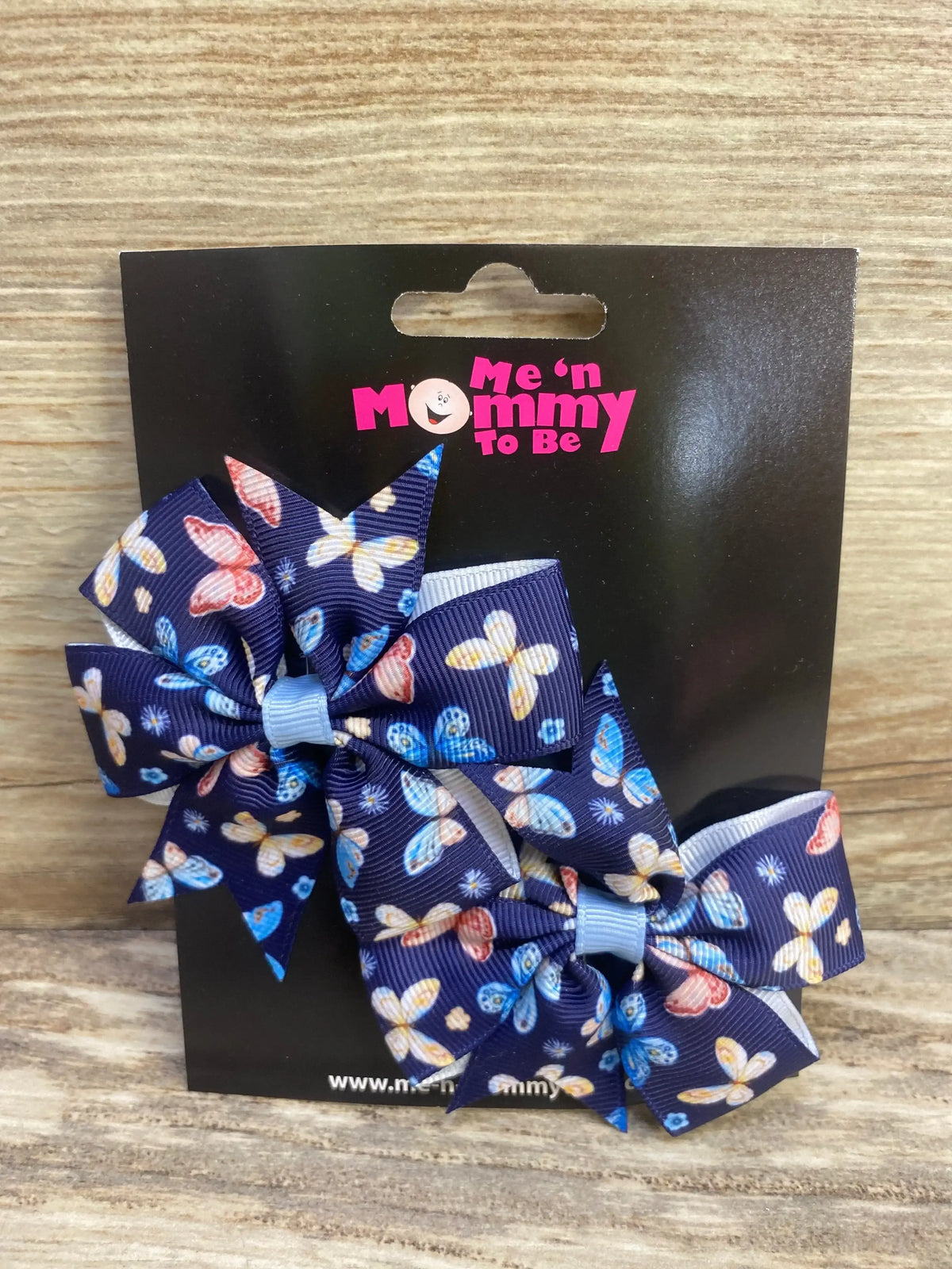 Front view of navy butterfly fanned-out hair bows 2-pack showcasing light-blue centers on black card and wood background