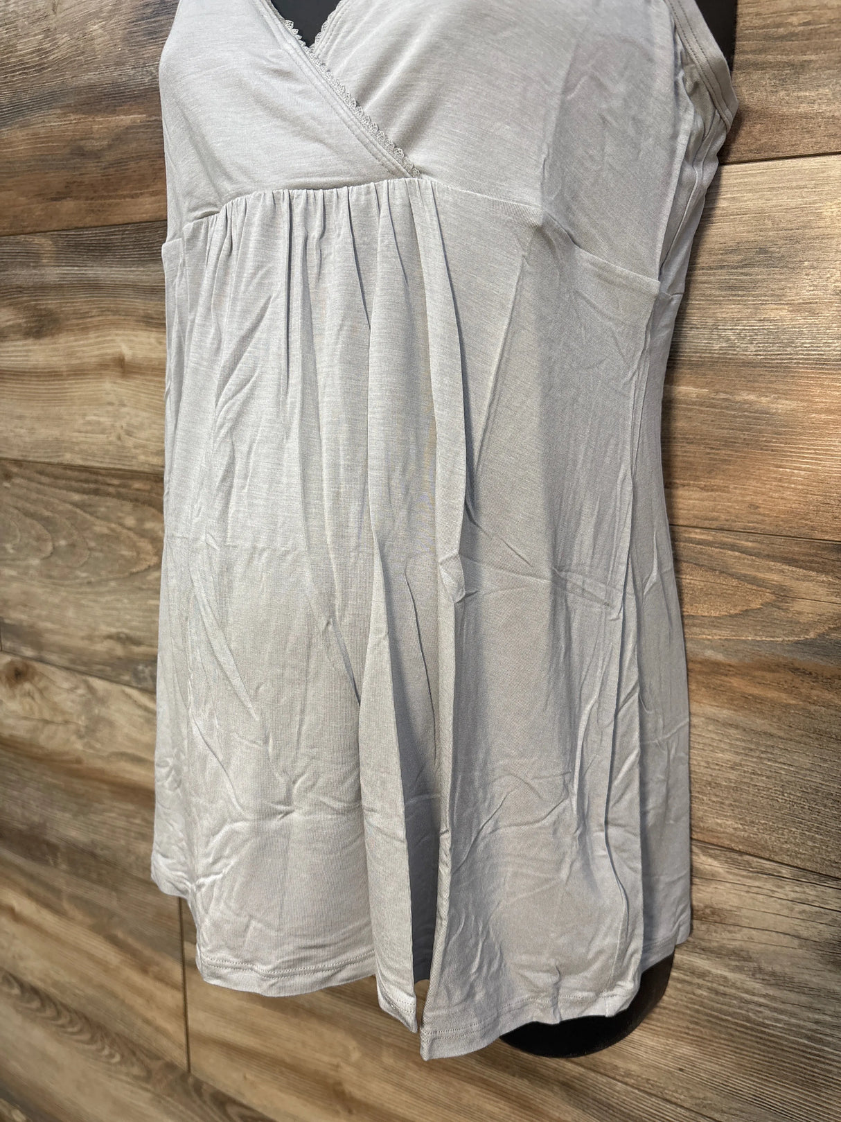 Light grey sleeveless nightgown with lace trim on mannequin, wood background