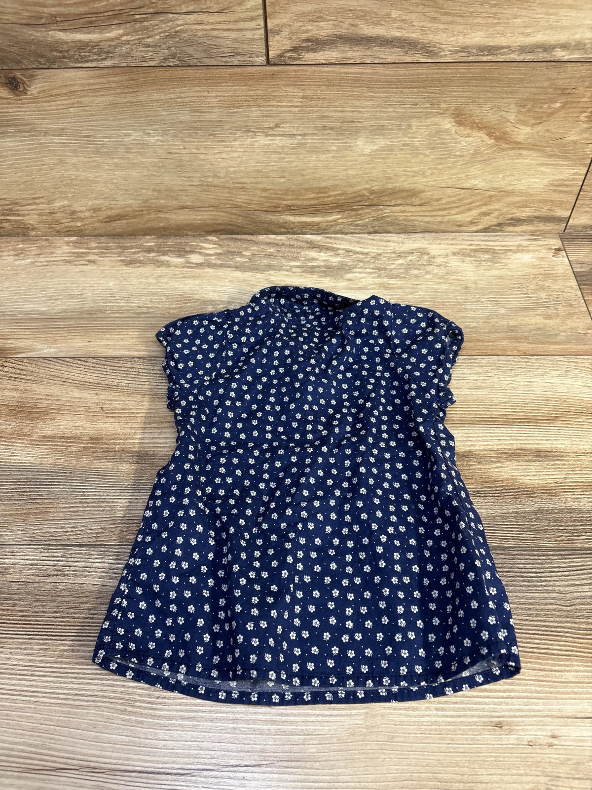 Front view of H&M floral collared shirt dress showcasing navy floral print and flared skirt on a wood background