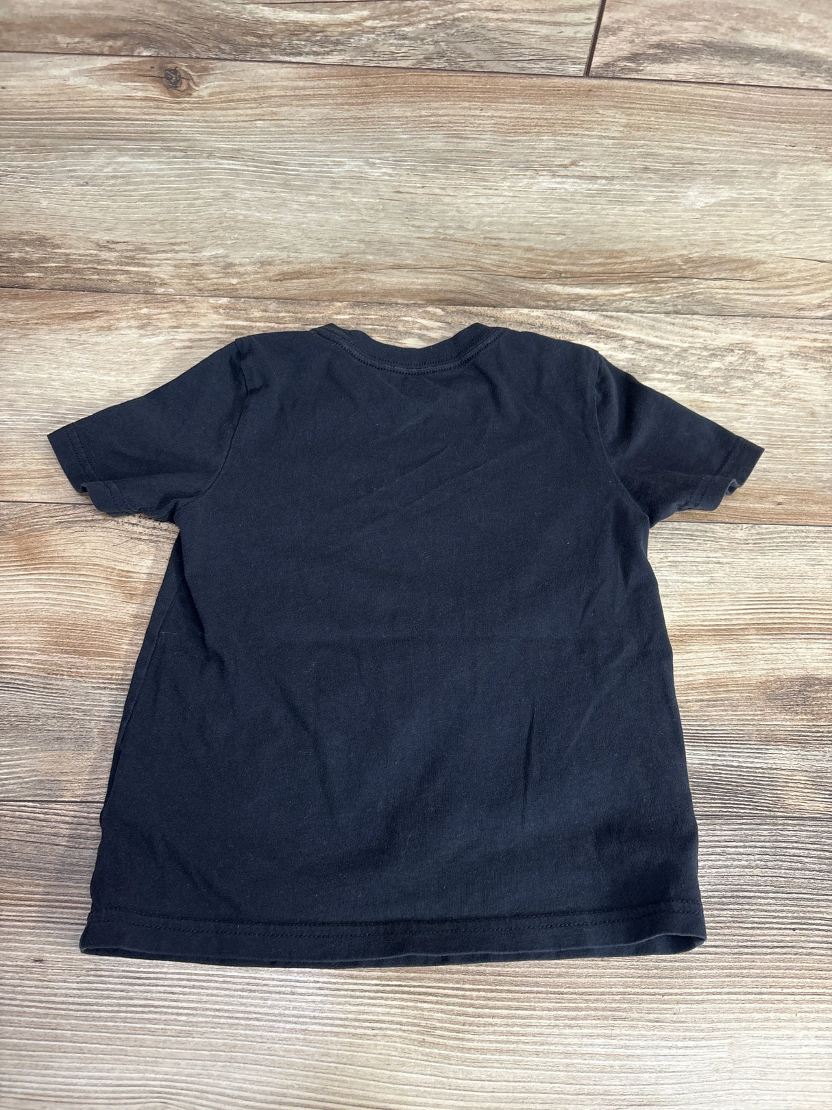 Black short sleeve kids t-shirt displayed on wooden background, back view
