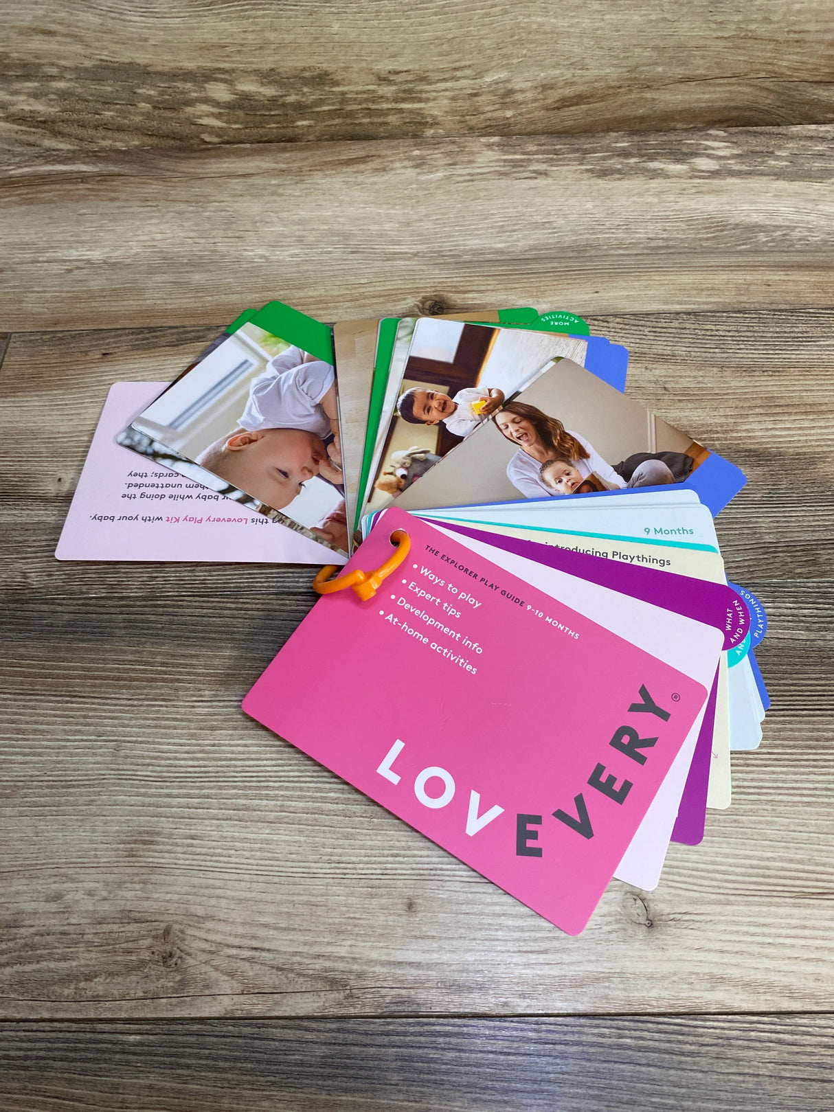 Lovevery play guide cards on wooden floor, featuring expert tips and baby activities
