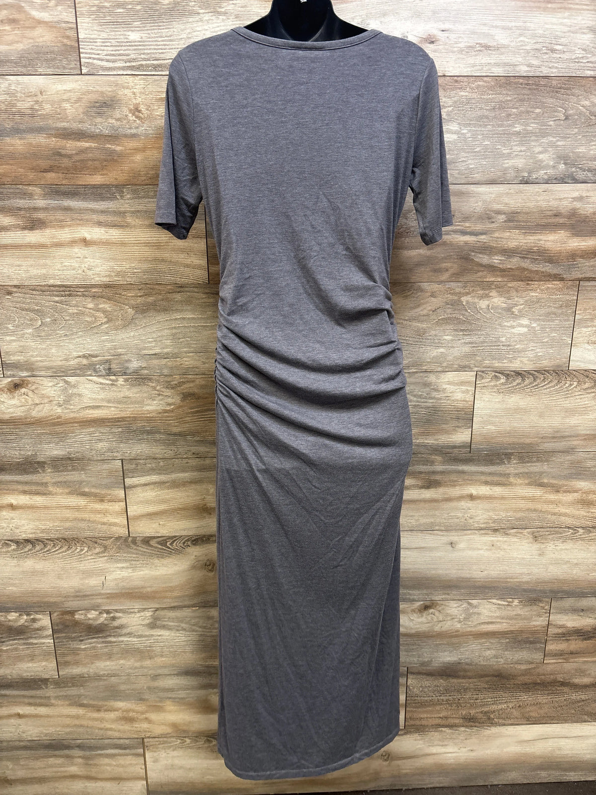Back view of a grey Motherhood Maternity bodycon dress on a mannequin against a wood wall.