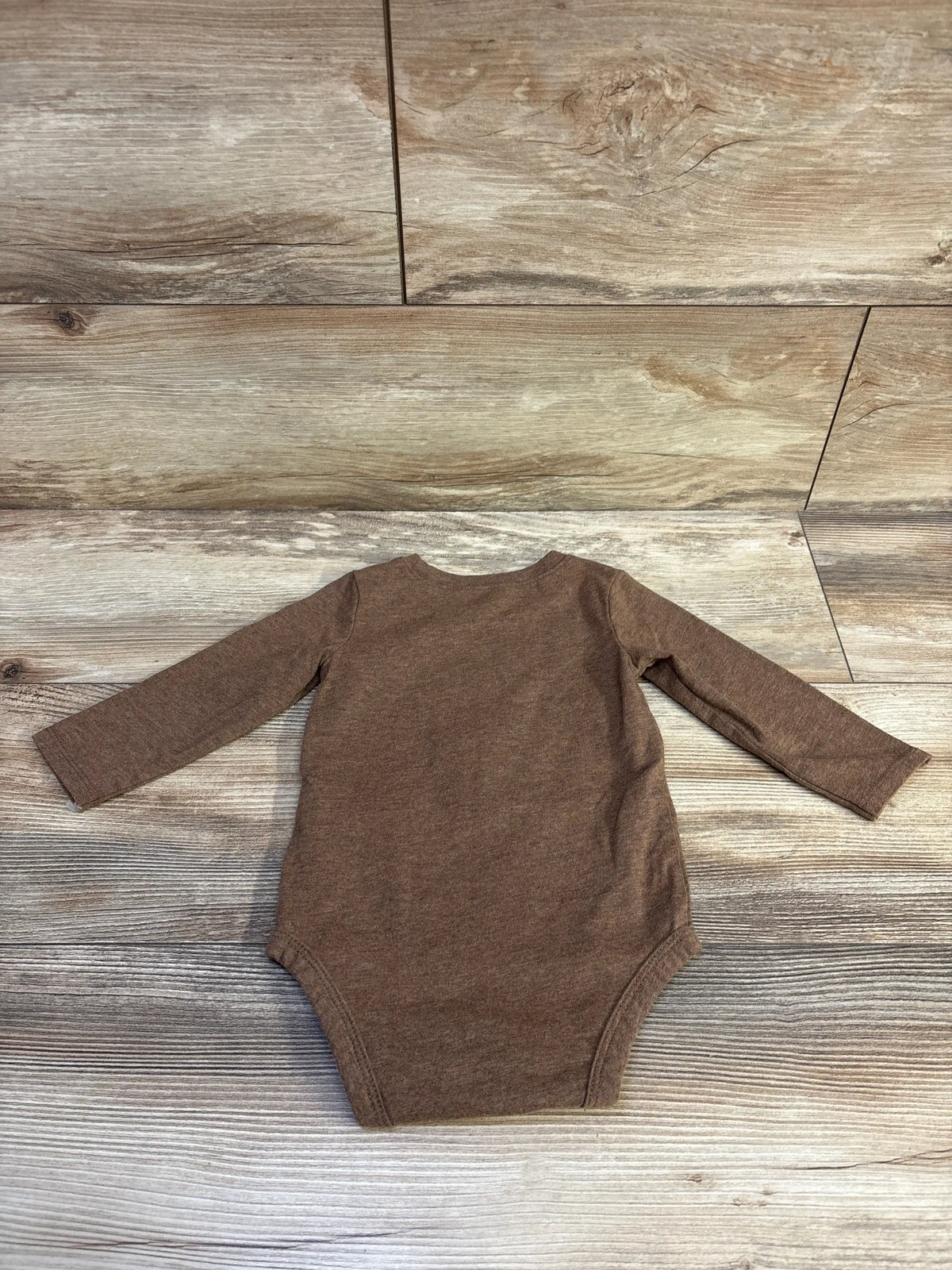 Front view of Carter’s brown long-sleeve baby bodysuit on a wood-look background