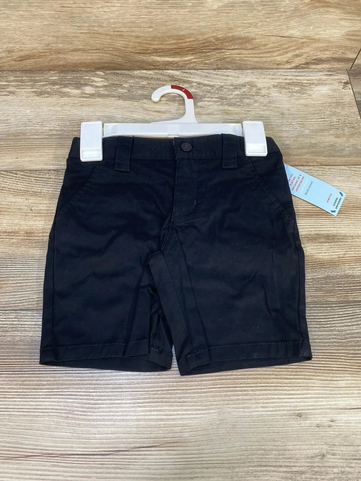 Front view of Cat & Jack black toddler (4T) school uniform shorts showing buttoned waistband, belt loops and front pockets on wood background