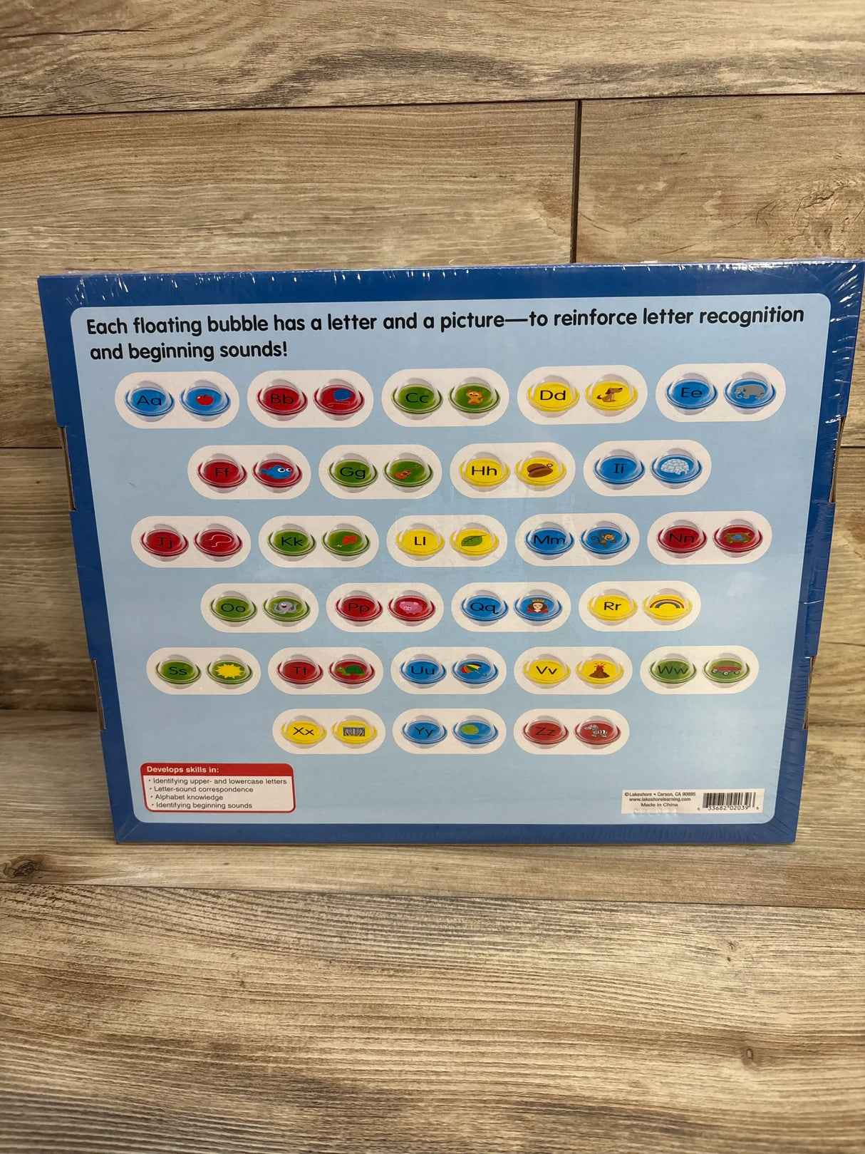 Rear of Float & Find Alphabet Bubbles box with letter-and-picture floating bubbles, header reinforces letters on wood