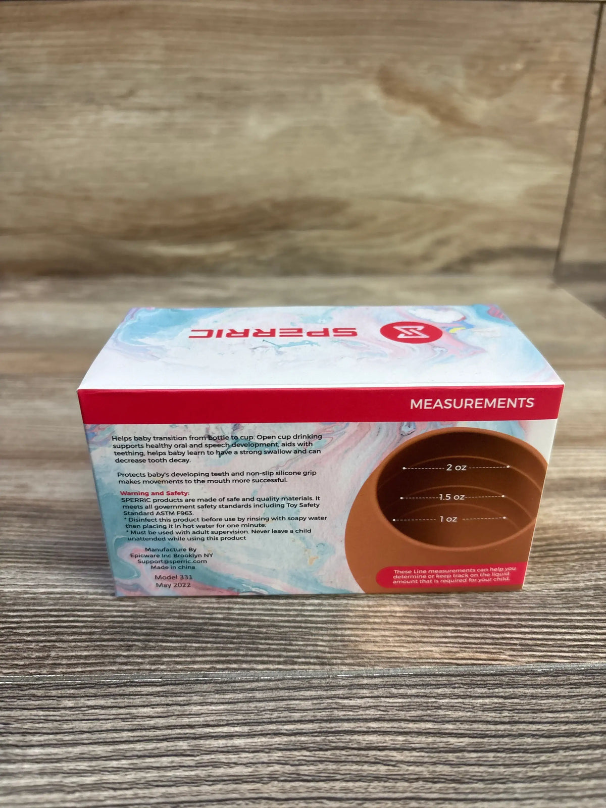 Front of Sperric silicone baby cups 3oz 2-pack box showing measurement markings (1, 1.5, 2 oz) and product text on wood tabletop