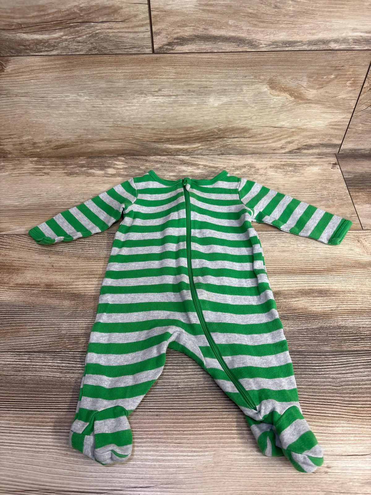 Green and gray striped baby footed sleeper with zipper on wood floor