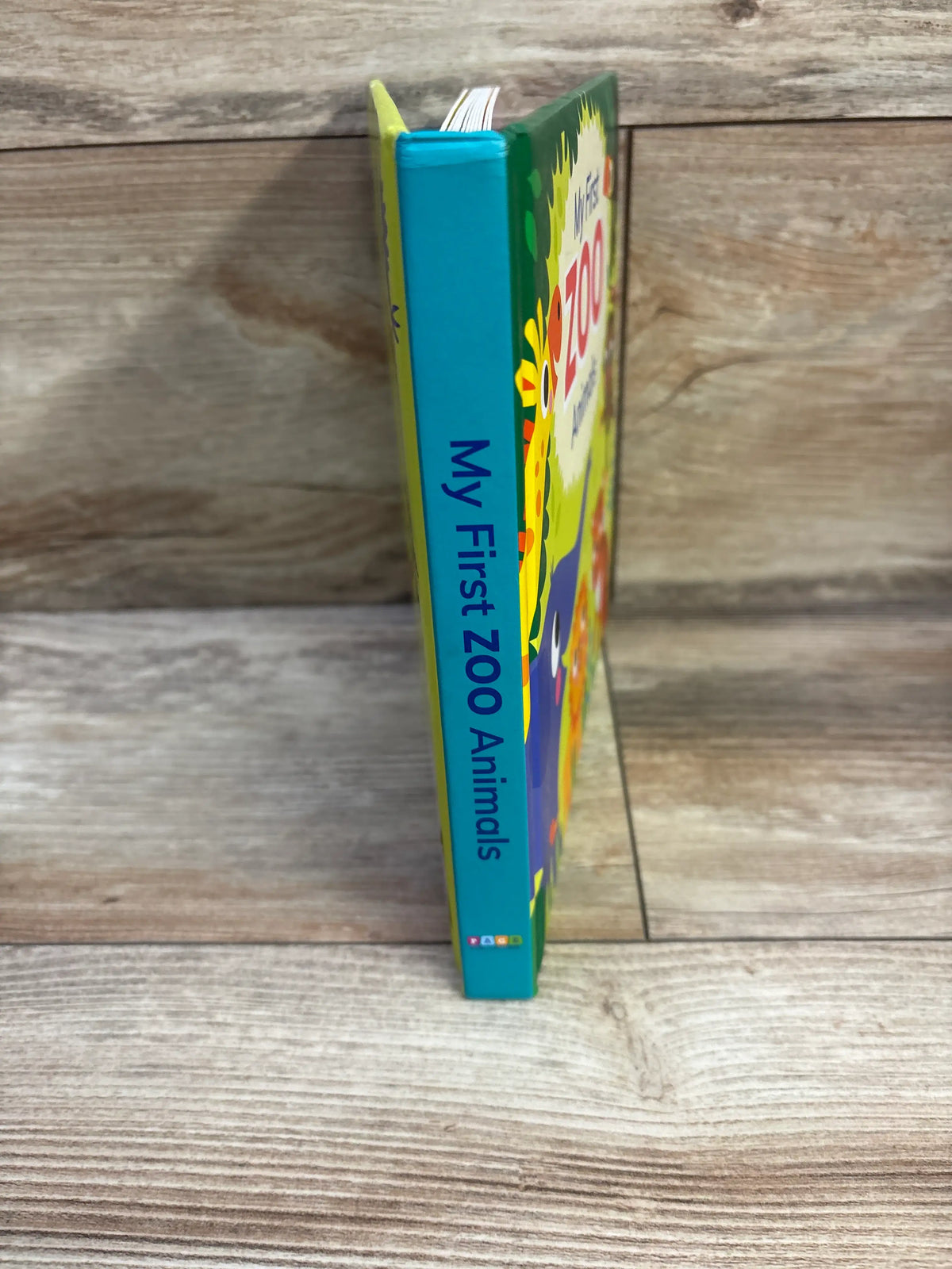Side view of My First Zoo Animals board book showcasing its colorful illustrated cover and spine with a wood background