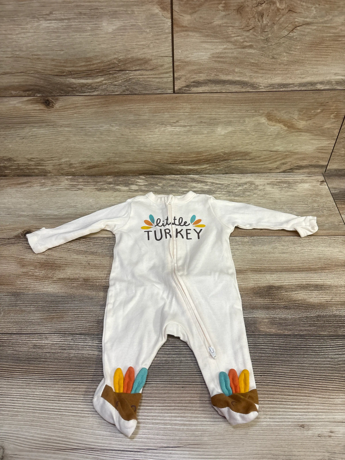 Front view of Old Navy Little Turkey sleeper showcasing turkey graphic, zipper, and turkey feet with wood-look background